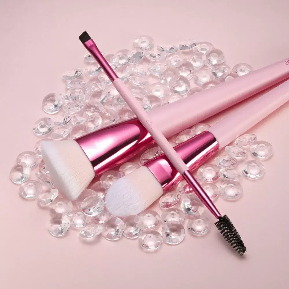 Rózsaszín make-up ecsetek gyöngyök között.