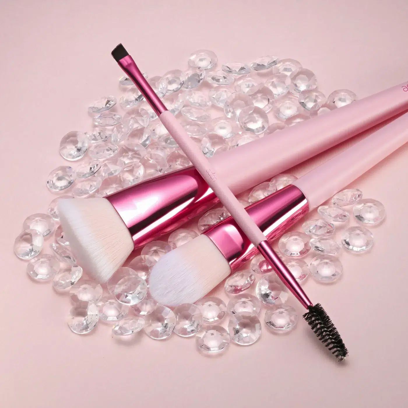 Rózsaszín make-up alapozó ecset gyöngyök között.